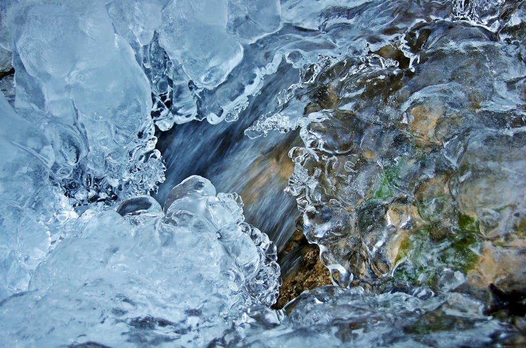 Detailed macro shot of ice formation over a flowing stream, capturing winter's natural beauty.